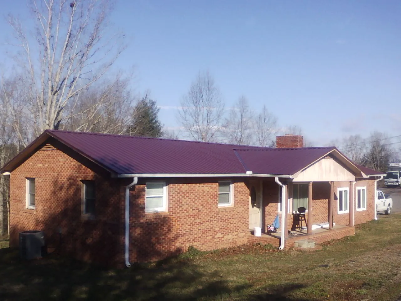 Burgundy metal roof on a brick ranch home with a new addition in Colton