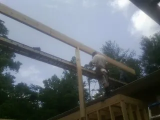 Carpenter setting a ridge beam over a new addition frame — Ice Dam Removal by Roofing Brothers in Colton